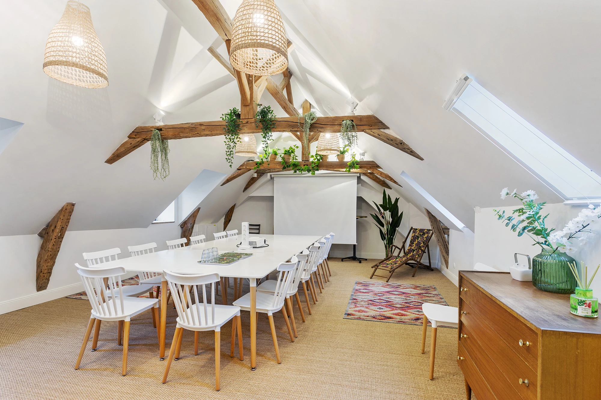 Salle de réunion sous combles avec grande table et poutres apparentes