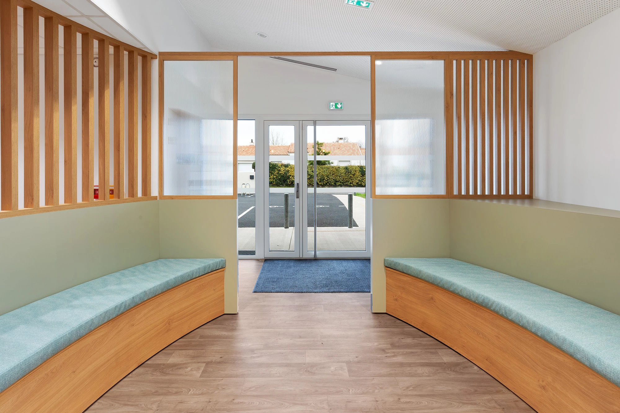 Entrée lumineuse avec claustra en bois, assises intégrées sur mesure et porte vitrée donnant sur l’extérieur.