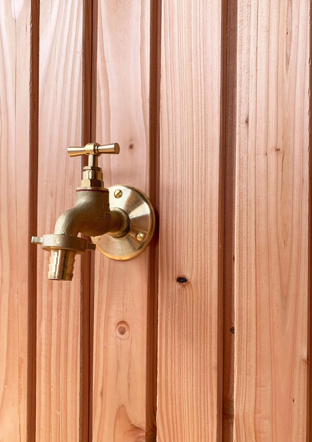 Robinet extérieur en laiton fixé sur bardage en bois