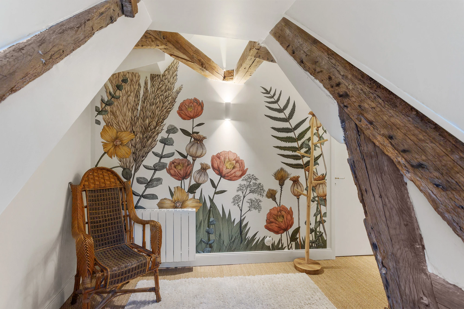 Coin mansardé avec fauteuil en osier et fresque florale