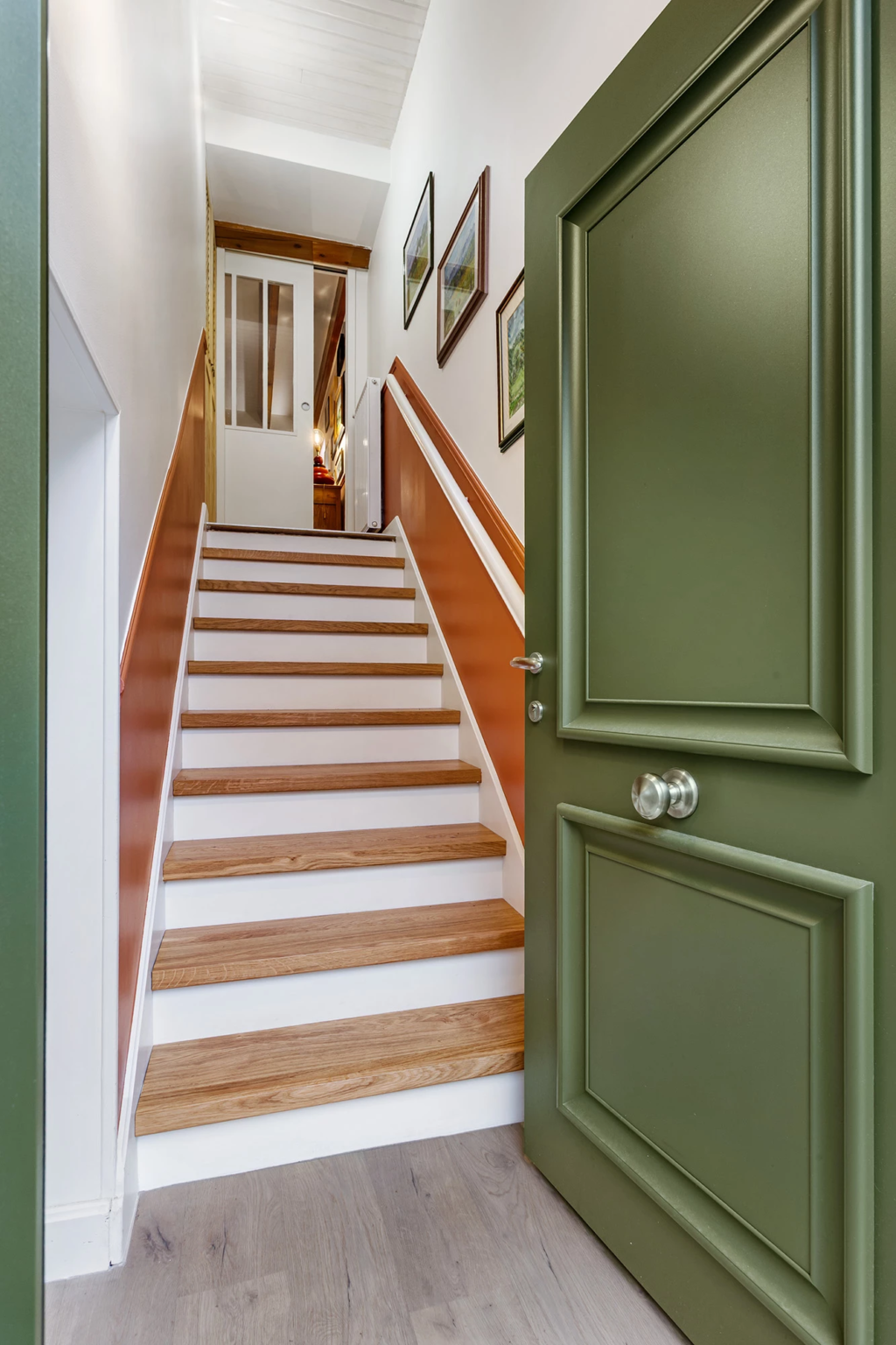 Entrée avec porte verte ouverte sur escalier intérieur en bois