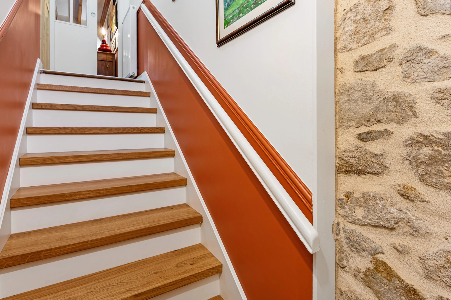 Escalier intérieur en bois avec mur terracotta et rampe blanche