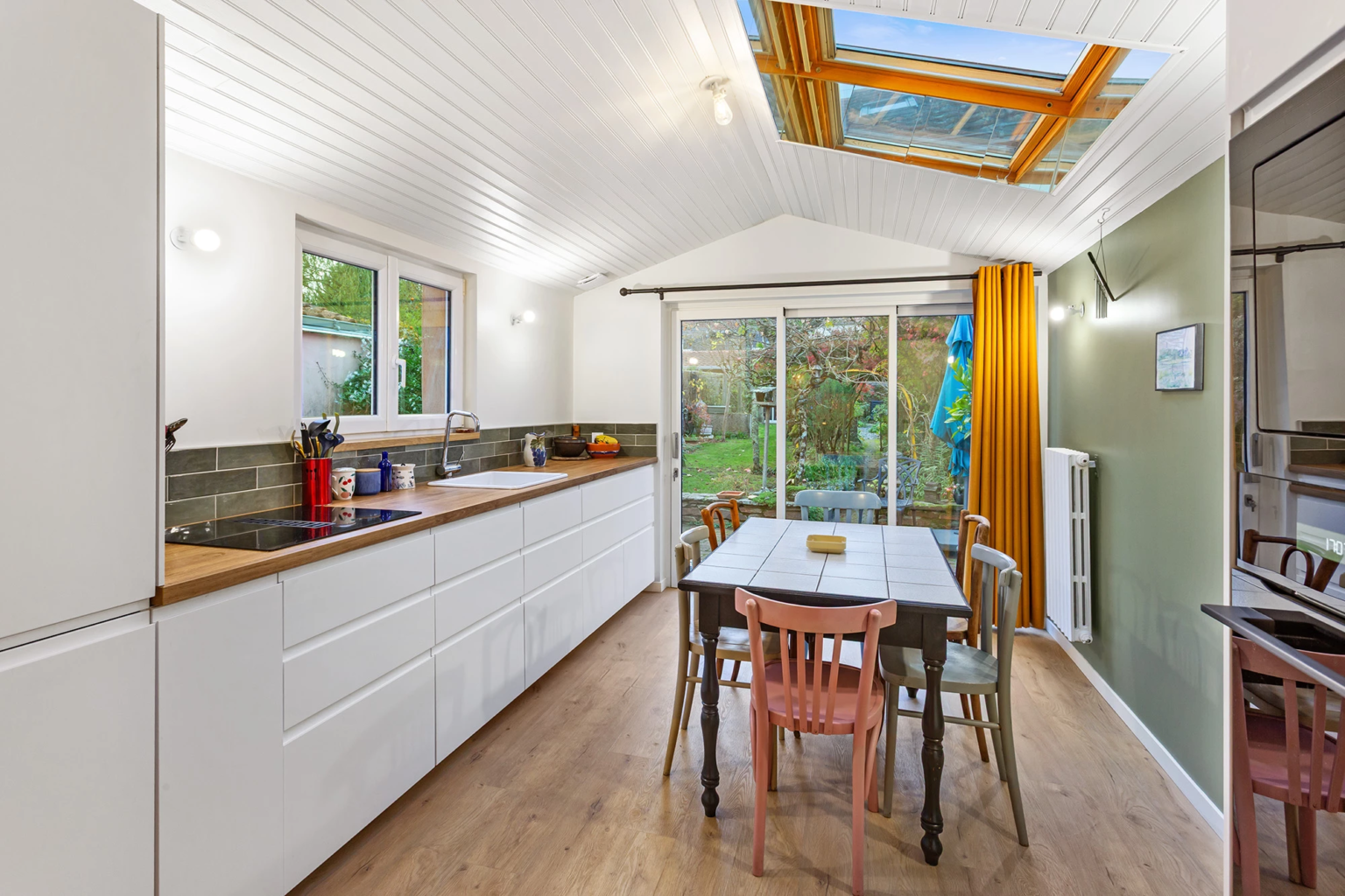 Cuisine lumineuse avec table à manger et baie vitrée sur jardin