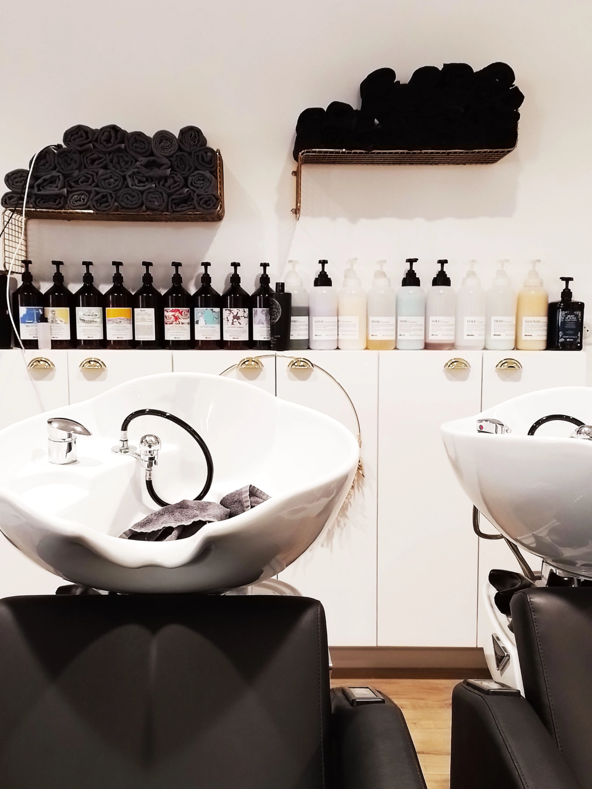 Bacs de lavage avec fauteuils noirs et produits alignés