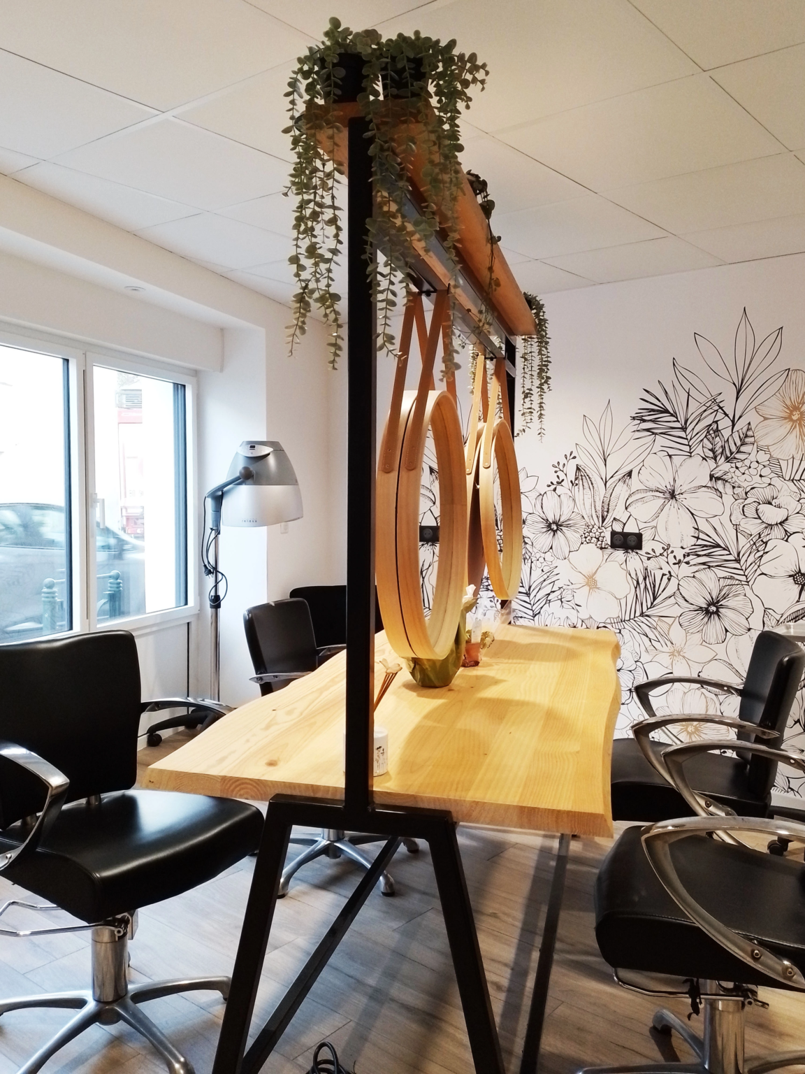 Table de coiffure centrale avec miroirs suspendus et plantes